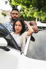 Hispanic couple standing by white car traveling together