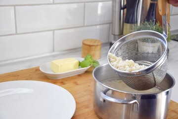 A person scoops up the cooked pasta with a special colander, where the water is immediately drained.