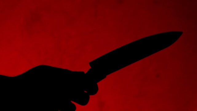 Silhouette man holding knife in red light. The shadow of a murderer kills his victim with a knife at night.