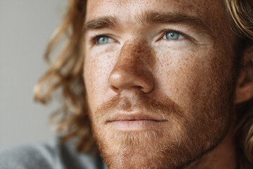 Fototapeta premium Portrait of a young man with blue eyes and freckles indoors