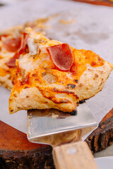 Close-up of a delicious pepperoni pizza slice being lifted by a spatula, featuring a satisfying cheese pull and crispy crust