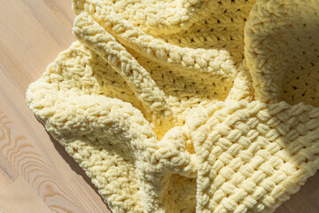textured yellow knitted blanket draped on a wooden surface in soft light
