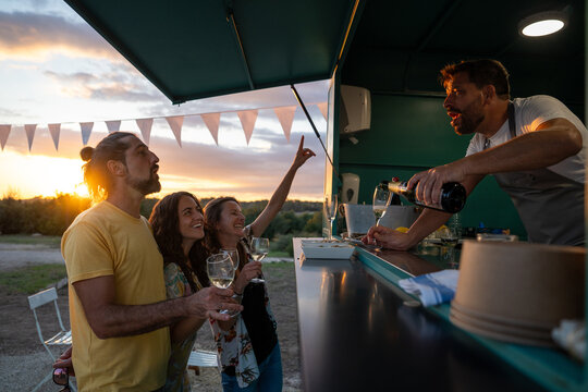 Friends enjoying celebration with drinks from a food truck - Powered by Adobe