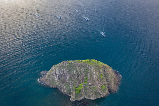 Aerial view of a solitary, verdant island rising from the turquoise sea, as boats leave white wakes across the vast expanse of water, Hon Yen, Ph&Atilde;&ordm; Y&Atilde;&ordf;n, Vietnam.