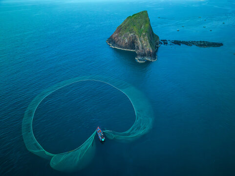 Aerial view of a fishing boat casting a large net in the turquoise sea near Hon Yen islet, Ph&Atilde;&ordm; Y&Atilde;&ordf;n, Vietnam.