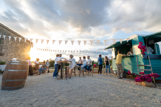 Friends enjoying drinks at outdoor food truck party at sunset