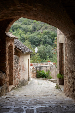 Cobblestone path leading to a stone archway in a rural village