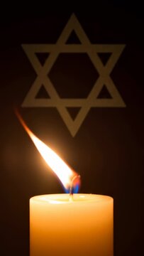 Lit remembrance candle with star of david casting shadow, symbolizing solemn observance footage for memorial day.