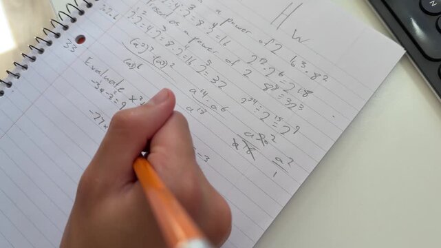Student doing math homework with a number 2 pencil and erasing a mistake on a lined notebook paper.