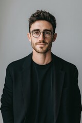 Obraz premium A confident young man with glasses dressed in a black blazer and black shirt.