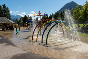 Outdoor waterpark with colorful rainbow arches creating a fun splash zone. © Viks
