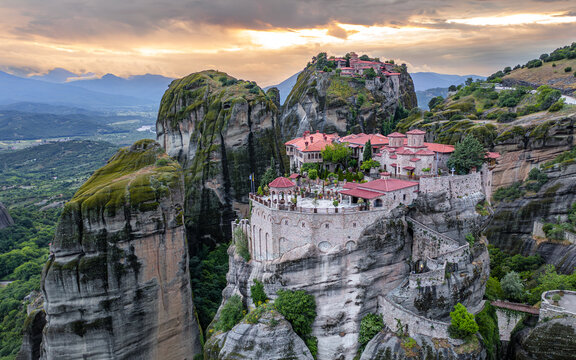 Aerial view of monasteries perched atop towering rock formations, bathed in the golden light of dusk, creating a serene and mystical landscape, Kalabaka, Trikala, Greece.