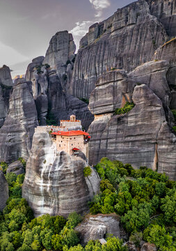 Aerial view of the Monastery of Rousanou perched atop a monolithic pillar, its red-tiled roof a vibrant contrast to the gray rocks, Kalabaka, Trikala, Greece.
