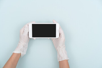 Holding a mobile phone with hands wearing disposable gloves
