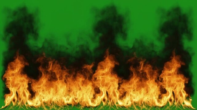 Realistic fire wall with intense flames and rising black smoke isolated on a green screen for easy chroma key video compositing