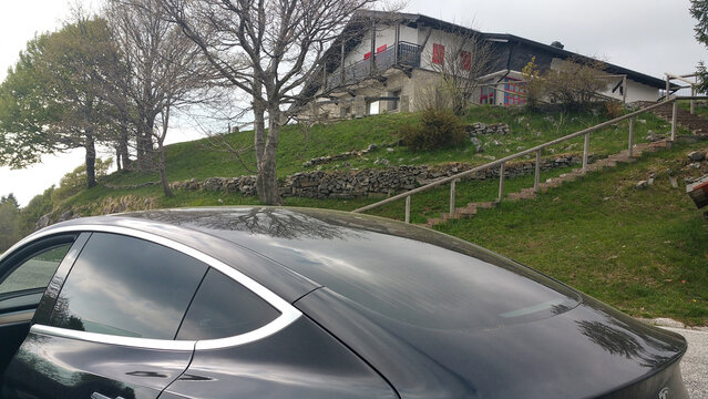 Savogna, Italy - May 04, 2020: Matajur Mountain, a static shot of a solid black Tesla Model 3 dual motor long range awd with tinted windows and aero wheels in a cloudy spring day