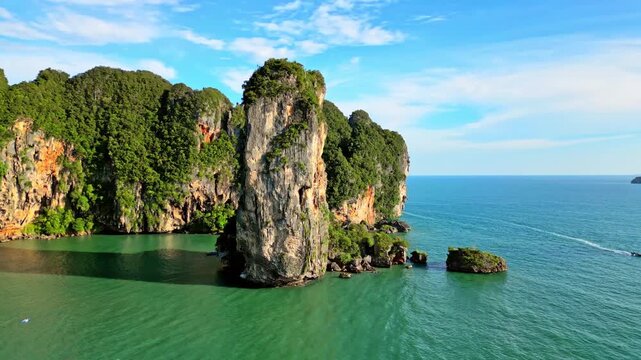Aerial view of striking limestone cliffs covered in lush vegetation meeting the turquoise waters in Ao Nang, Krabi, Thailand.