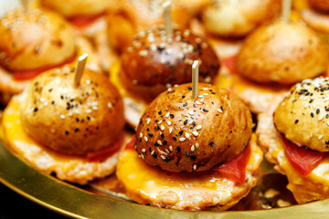 Mini burgers with sesame buns and cheese on serving tray