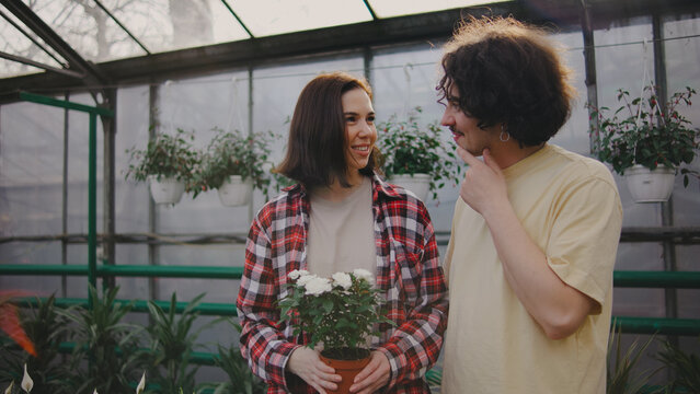 Couple enjoys planting flowers together in a greenhouse during a sunny afternoon