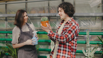 Engaging conversation between two people in a greenhouse while caring for plants during a sunny afternoon
