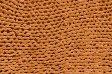 Macro, close up, detailed orange knitted textile, fabric texture with chunky yarn pattern suface. Cozy handmade cloth background, knitwear backdrop , perfect for design, crafts, warm winter concept