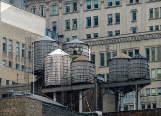 View of water towers stand sentinel atop buildings, a metallic cluster against the textured facades, New York, New York, United States.