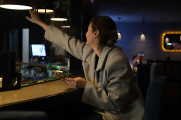 Attractive young woman is sitting at the bar counter in nightclub. 