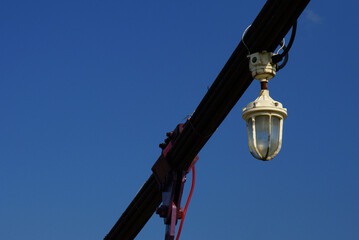 Fototapeta premium A white industrial lamp hanging on a bridge cable.