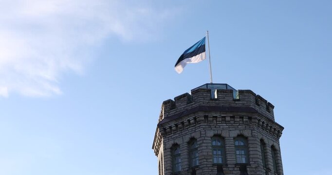 Close-up architectural view of a historic stone tower with the Estonian fla in Tallinn, Estonia. Crisp daylight, clear blue sky