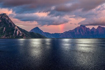 Empty wet asphalt road and beautiful mountain with spectacular sky clouds at sunset