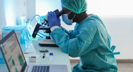 Medical workers in hazmat suit working with microscope inside laboratory hospital wearing safety...