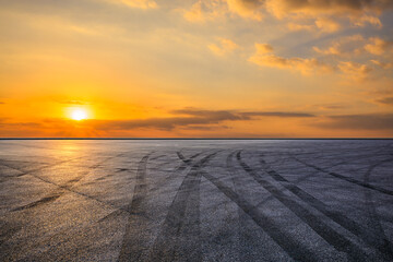 Empty asphalt race track with tire skid marks with beautiful sky clouds at sunset