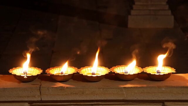 A serene row of traditional Indian oil lamps softly glowing in the dark.