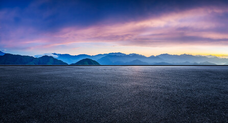 Empty asphalt road and beautiful mountain silhouette with spectacular sky clouds at sunset