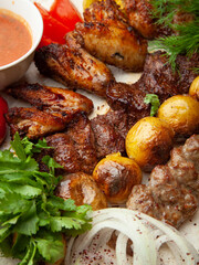 Grilled chicken wings and beef barbecue with baked potatoes