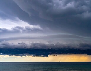 Over ocean, layered clouds meet dark sky; a storm descends