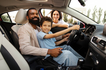 Happy Latin family with child son riding car, testing automobile, smiling at camera, preteen boy...