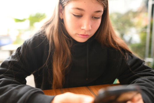 Beautiful young girl preoccupied with messages on her mobile phone.