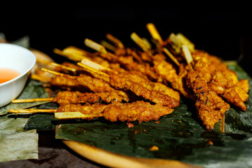 Chicken satay skewers with peanut sauce on banana leaves