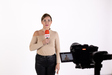 A female journalist is reporting in front of a camera with a microphone