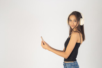 A young woman is standing and listening to music on her headphones 