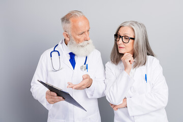 Fototapeta premium Senior doctors discuss patient care and diagnosis in a clinic while reviewing a clipboard and stethoscope