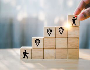 Hand placing a block with a figure holding a flag on a staircase, symbolizing career growth and achieving a goal.