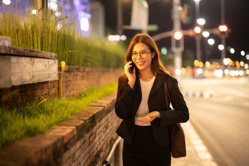 Fototapeta premium Asian businesswoman walking smiling talking on phone in city