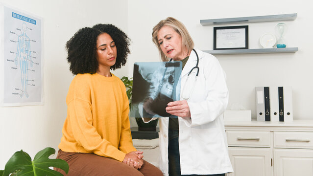 Doctor And Patient Review X-ray Image During Medical Consultation In Clinic Setting