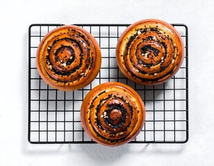 Overhead shot of three freshly baked, poppy-seed swirl buns on a wire rack