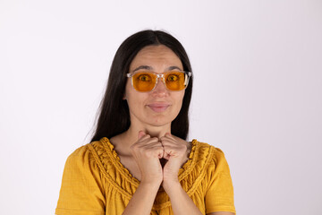 The woman is looking at the camera with her hands clasped under her chin