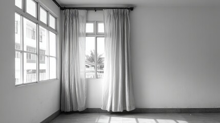Interior corner of an empty room illuminated by bright daylight streaming through multiple windows draped with sheer fabric