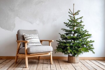 Simple evergreen tree decorated with subtle ornaments sits beside a minimalist wooden armchair indoors