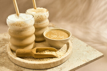 Sesame Tahini Latte Delight. Creamy sesame paste and iced tahini lattes on rustic travertine surface.